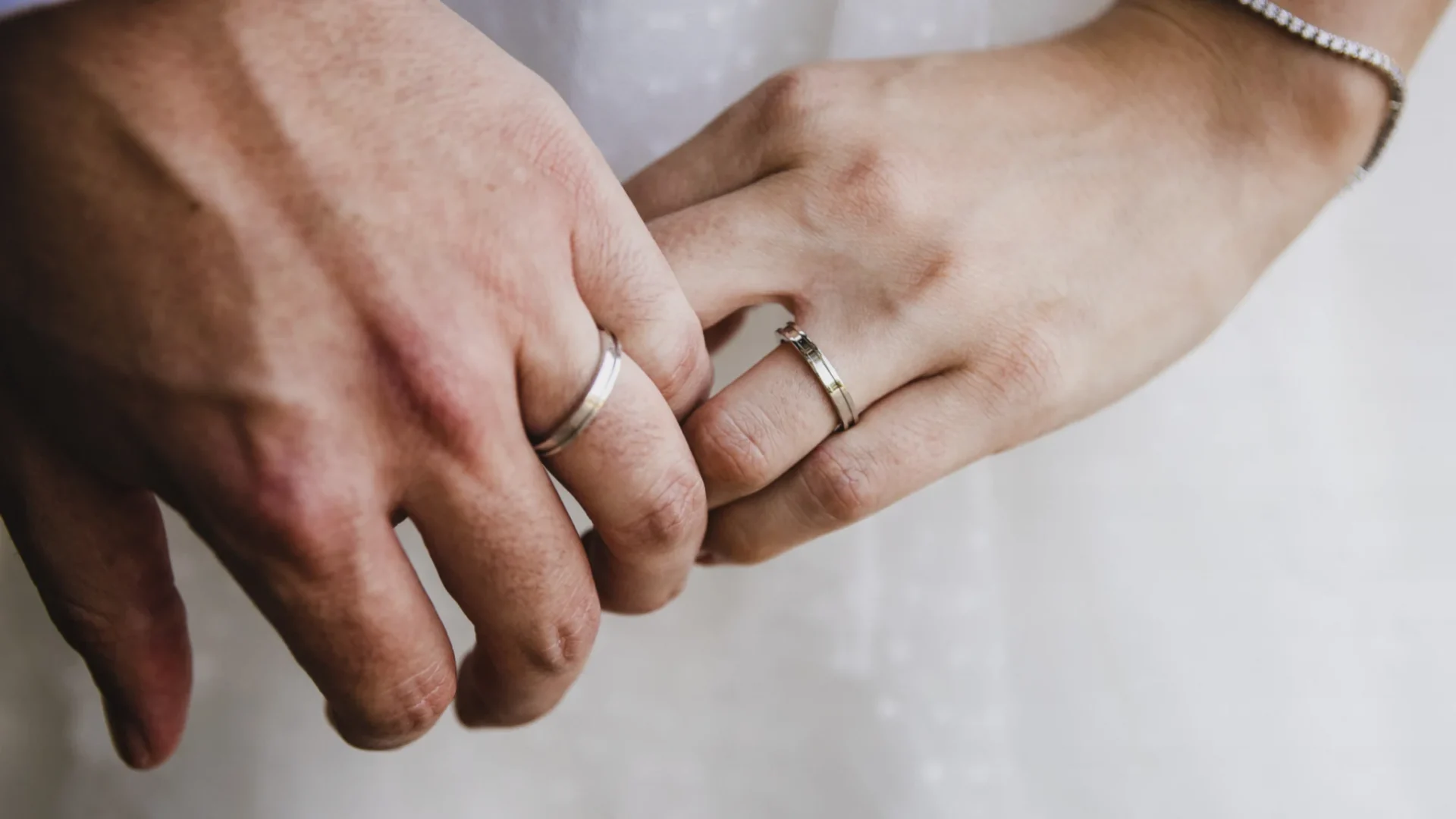 Close-up of a bride and groom’s hands with wedding rings during a wedding ceremony.