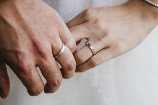 Close-up of a bride and groom’s hands with wedding rings during a wedding ceremony.