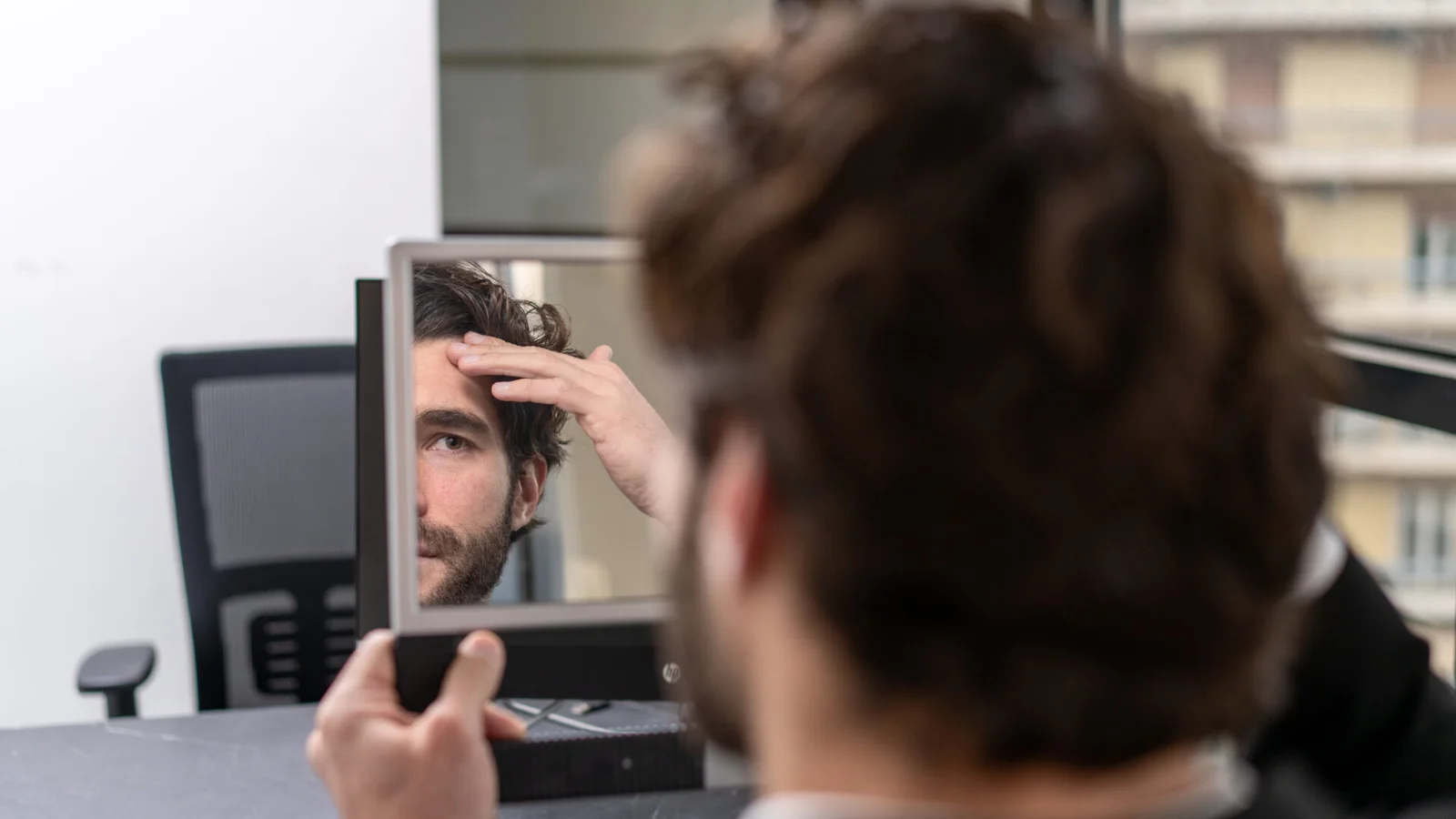 Άνδρας εξετάζει τη hairline του στον καθρέφτη στο πλαίσιο μακροχρόνιας στρατηγικής αντιμετώπισης ανδρικής τριχόπτωσης