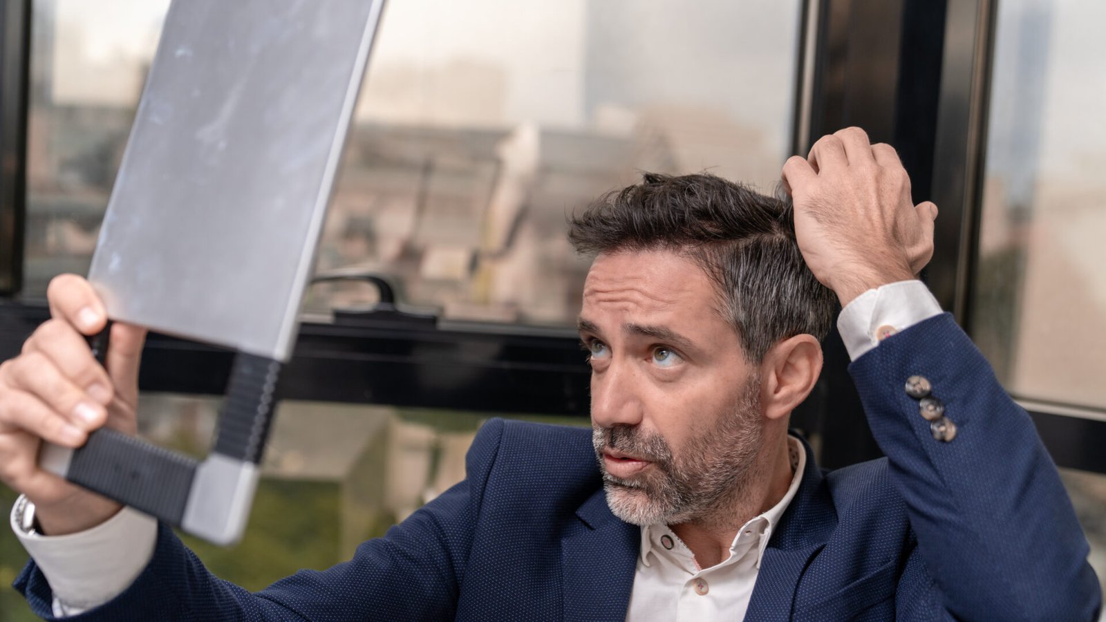 an checking his hair and scalp in a mirror during a hair consultation