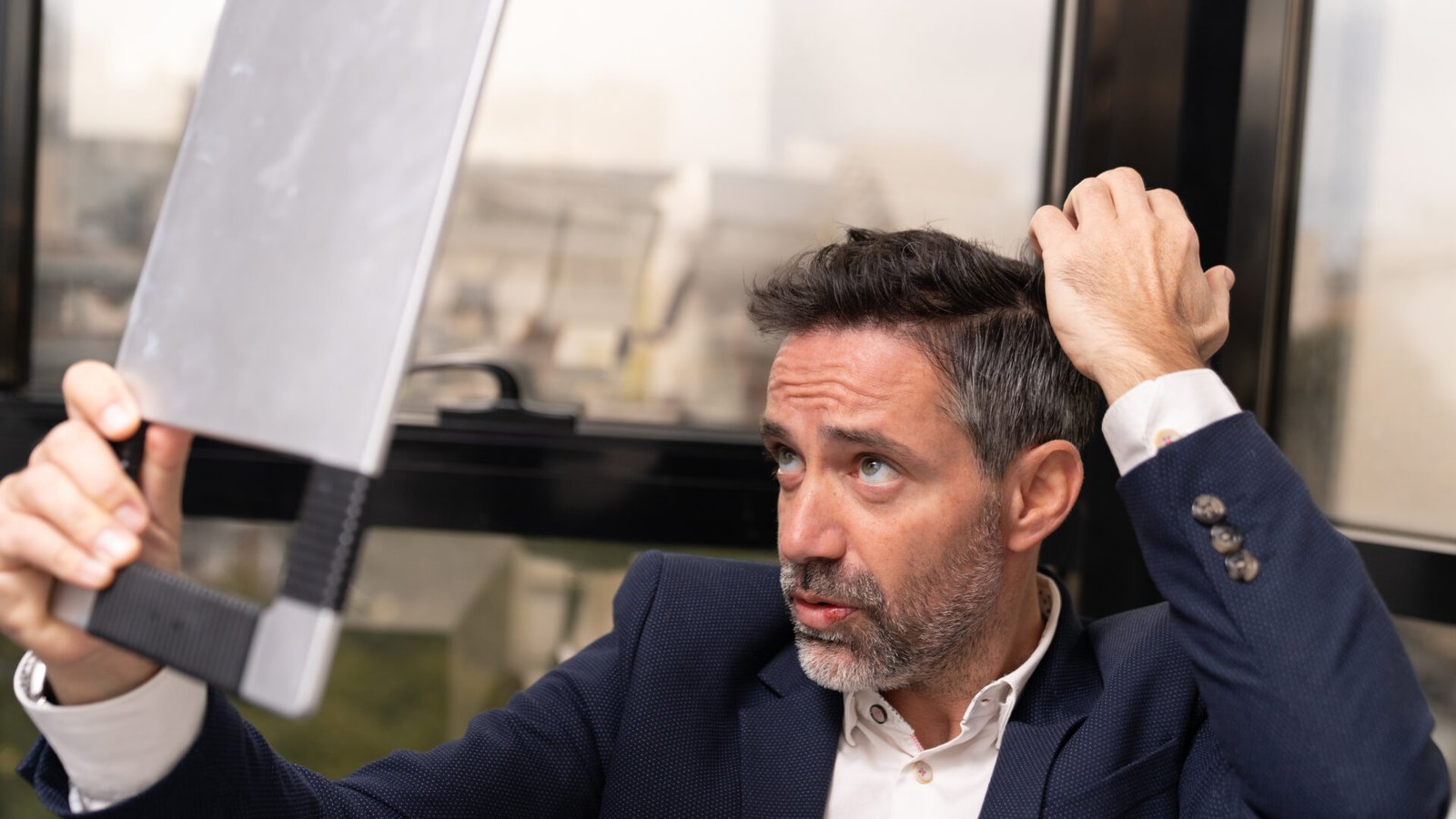 Man checking his hairline in mirror for early signs of hair loss
