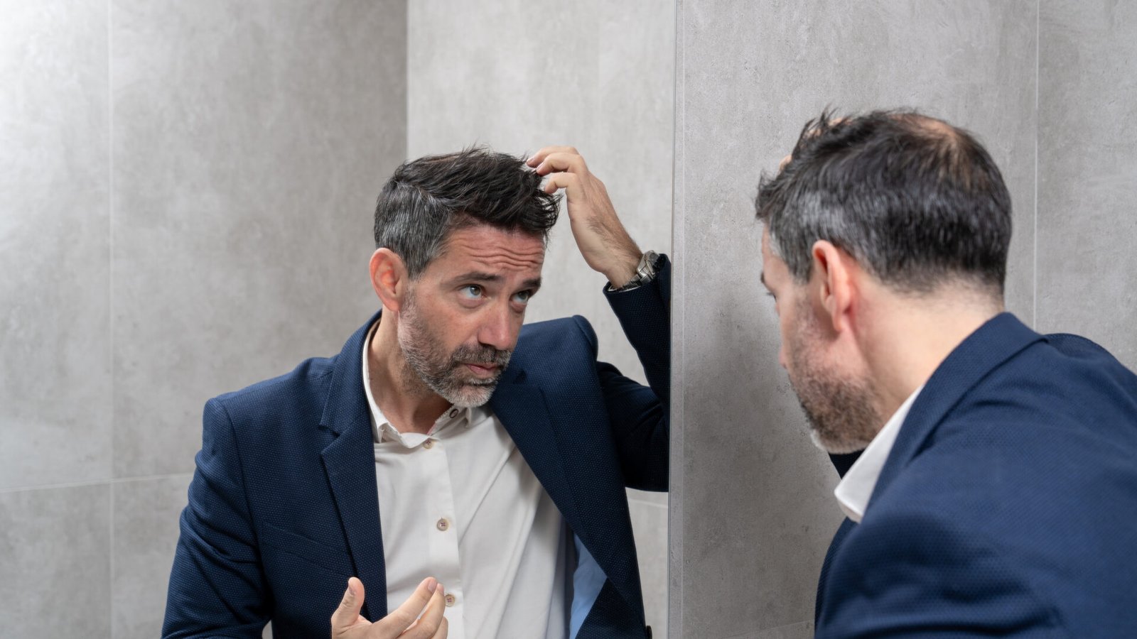 Man with hair thinning examining his hairline in the mirror