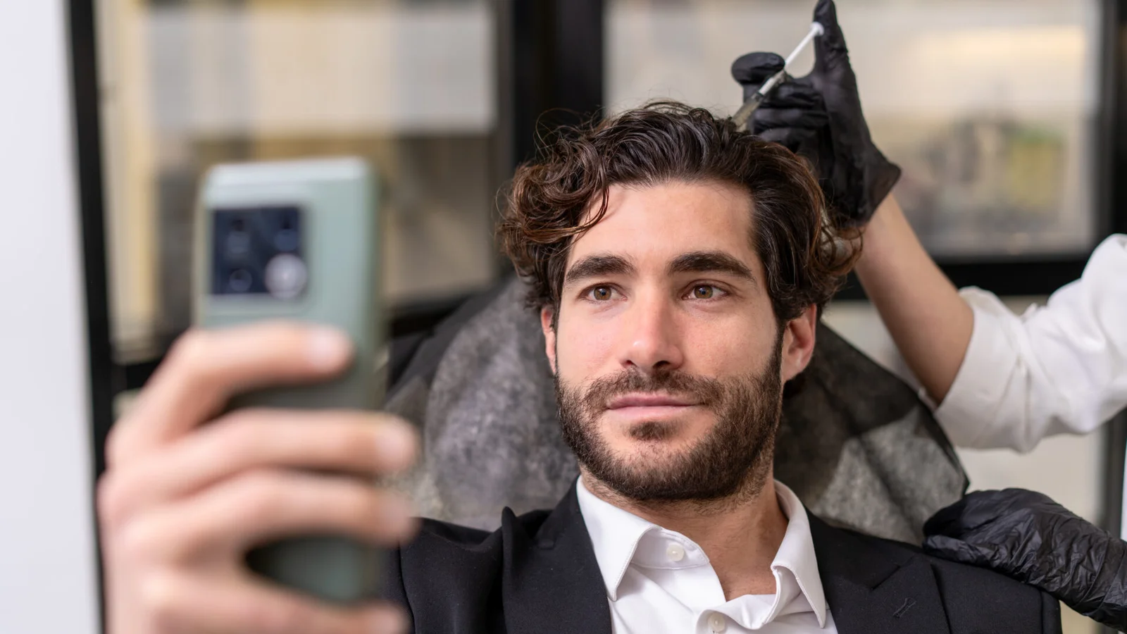 Άνδρας ελέγχει τα μαλλιά του κατά τη διάρκεια συμβουλευτικής συνεδρίας ενώ ειδικός εξετάζει το τριχωτό του